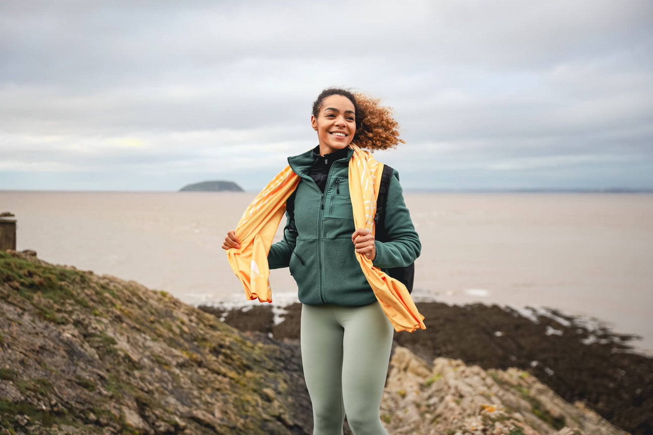 Woman laughing on a coastal path holding her Horizon travel towel